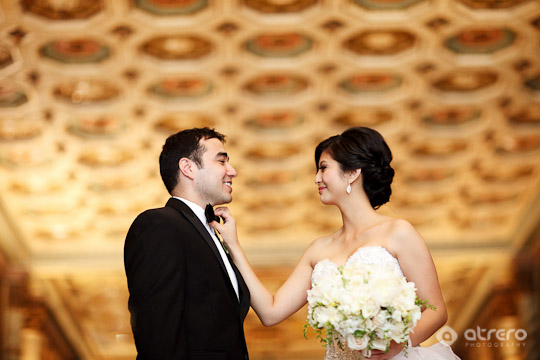 Happy bride adjusting groom's bow tie