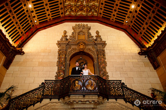 Happy couple posing on ornate balcony in grand building