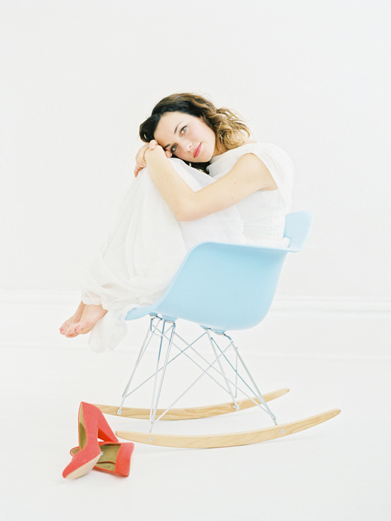 Woman in white dress sitting on a rocking chair indoors