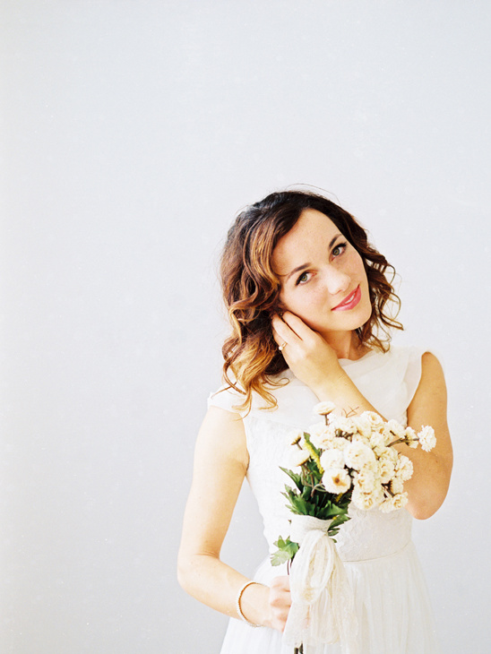 Bride with curly hair holding a bouquet of white flowers