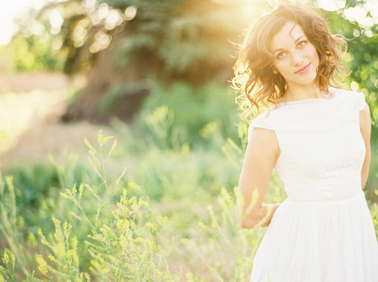 Woman in white dress smiles in the sunny green field