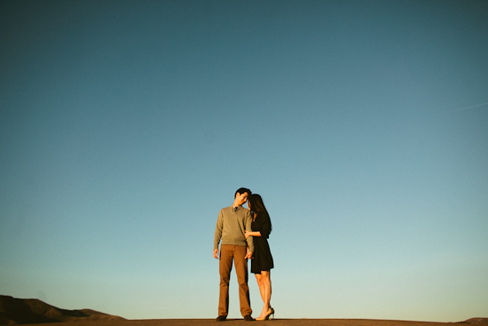 Couple embraces against a vast blue sky backdrop