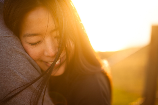 Asian woman hugging someone at sunset smiling