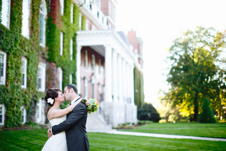 Newlyweds kiss in front of vine covered building