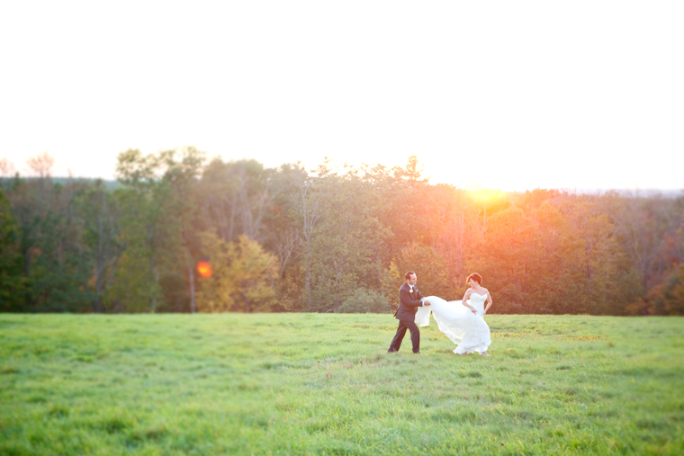 Bride and groom running in field at sunset wedding day