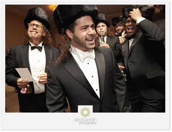 Groom and groomsmen in black tuxedos and fur hats