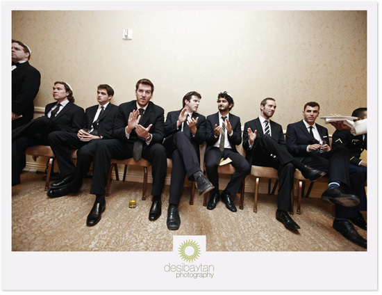 Groom and groomsmen in suits, seated for photo