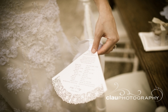 Bride holds lacy wedding program in hand at ceremony