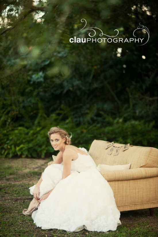 Bride in wedding dress sitting outdoors on vintage couch