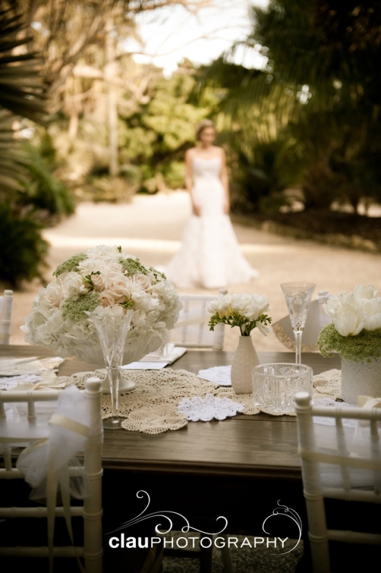Outdoor wedding table with floral decorations bride in background