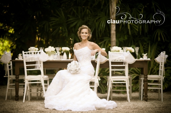 Bride in white dress sitting outdoors at wedding table