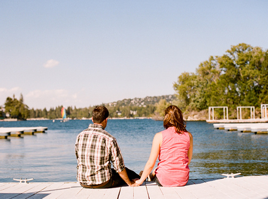 Couple sitting by lake, enjoying scenery