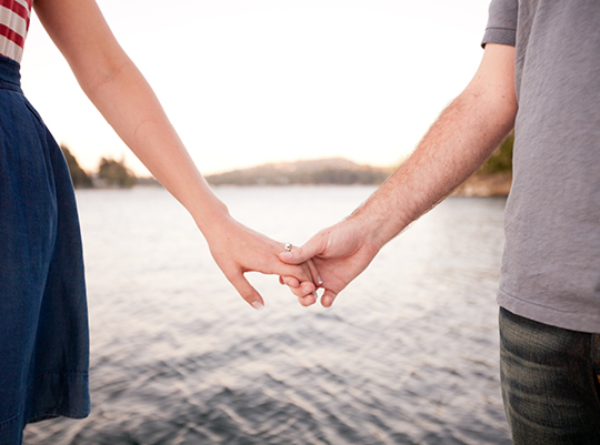 Loving couple holding hands by the lake