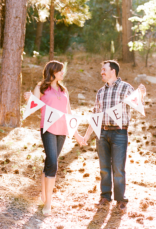 Happy couple holding a love banner in a forest