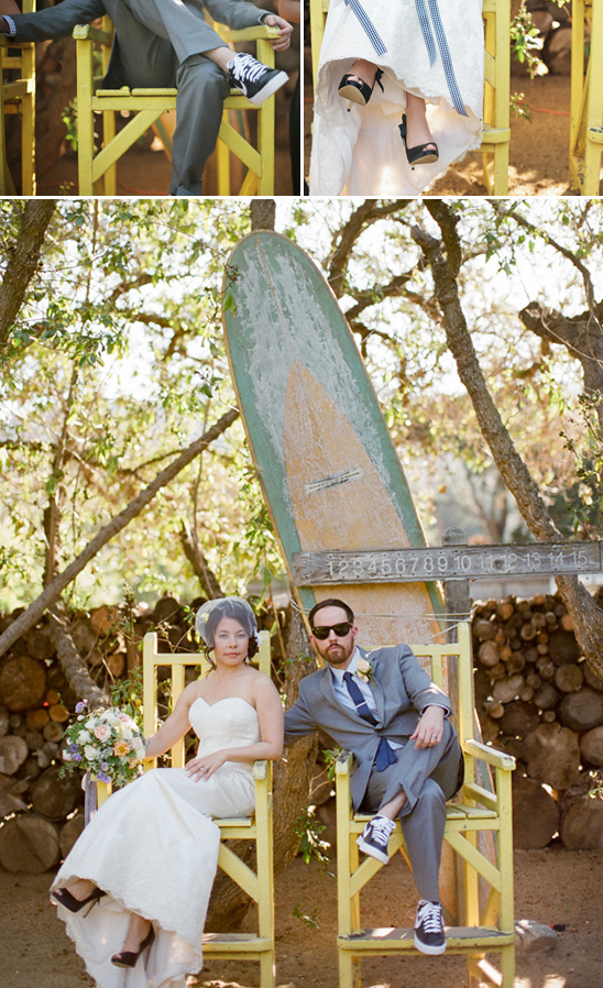Bride and groom posing on yellow chairs by surfboard