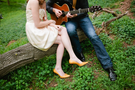 Couple enjoying music outdoors, sitting on a log with guitar