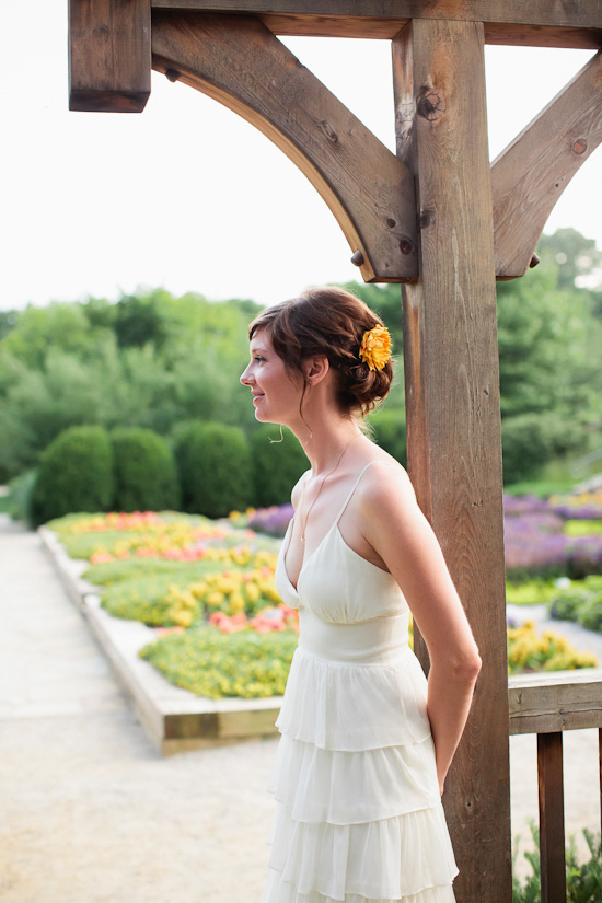 Bride in white tiered dress, yellow flower in hair