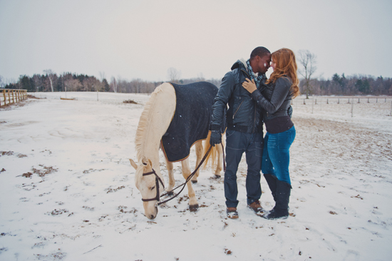 Couple shares a tender moment with their horse in snow