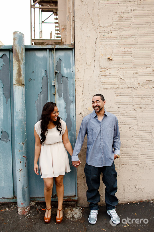 Smiling couple holding hands, near an old building in the city