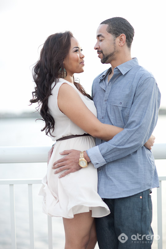 Couple embraces, gazing lovingly at each other near water outdoors