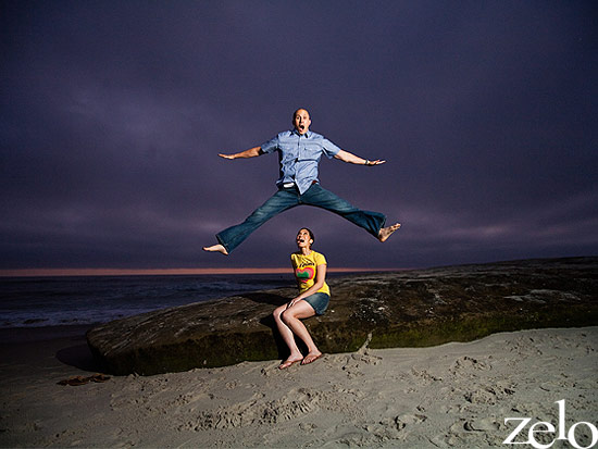Couple playfully jumping on a beach during sunset