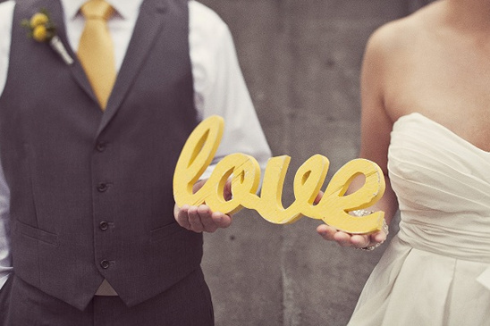 Wedding couple holding a yellow love sign together