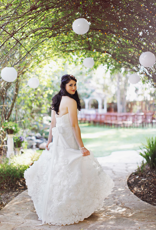 Bride in white gown under a garden archway