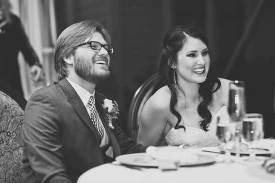 Bride and groom laughing at wedding reception speech