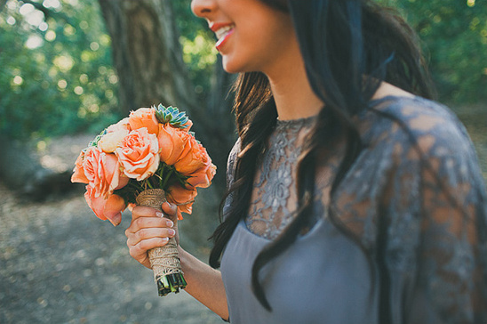 Woman smiles holding peach rose bouquet in nature