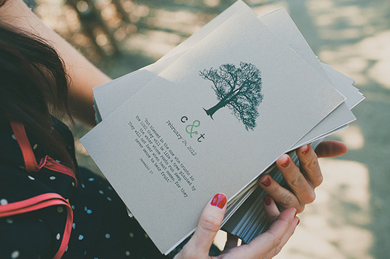 Hands holding wedding programs with tree illustration