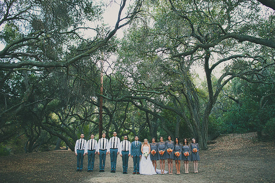 Bridal party poses beneath trees at outdoor wedding