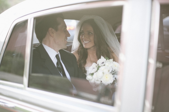 Bride and groom smiling in a car on their wedding day