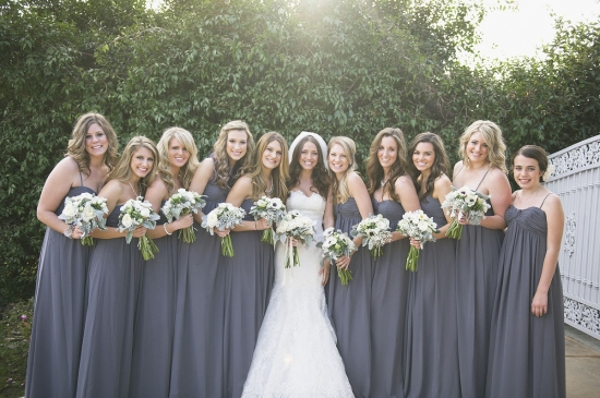 Bride and bridesmaids pose in elegant grey dresses with bouquets