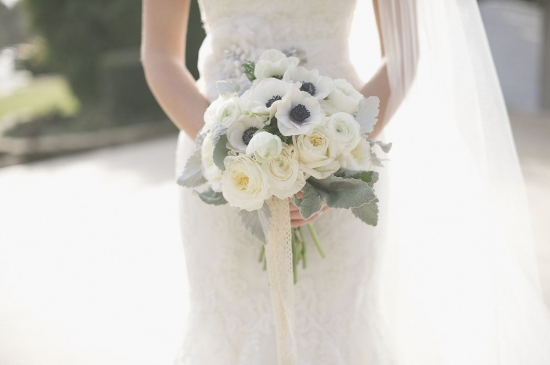 Bride holding a beautiful white wedding bouquet with lace ribbon
