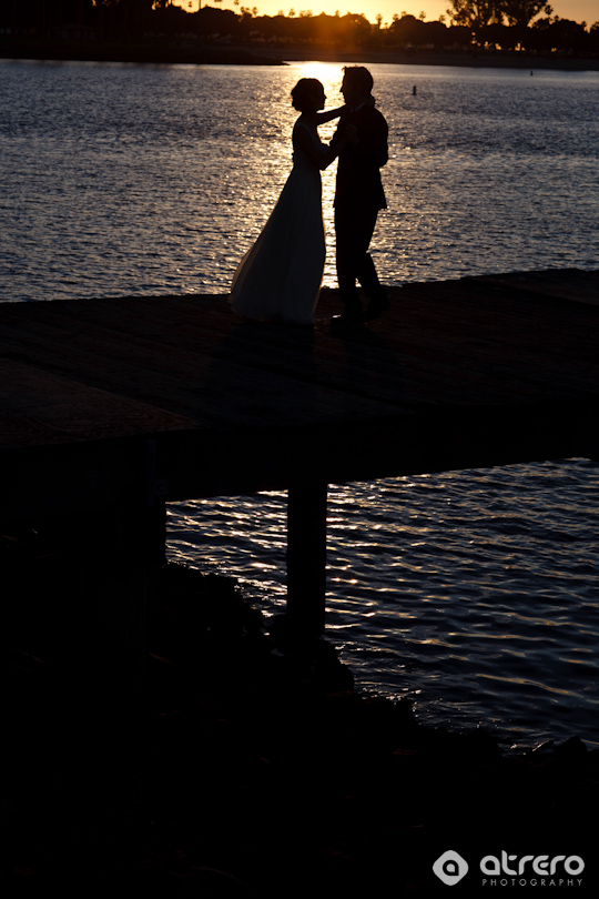 Silhouette of a wedding couple dancing on pier at sunset
