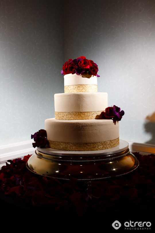 Elegant three-tiered wedding cake with red roses decoration on a gold platter
