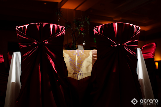 Elegant burgundy wedding chairs with satin bows at a formal event