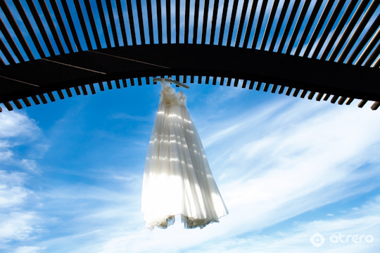 Wedding dress hanging under the wood structure with the sky background