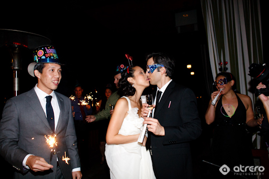 Couple kissing at a New Years Eve wedding with sparklers and party hats