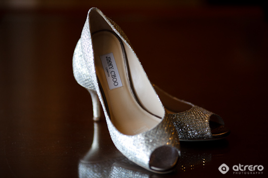 Elegant silver Jimmy Choo heels reflect on a dark, glossy surface