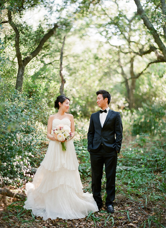 Happy couple in wedding attire, posing in a forest