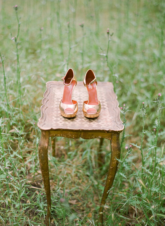 Gold wedding shoes on ornate table outdoors