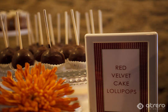Red velvet cake lollipops on a platter with orange flower