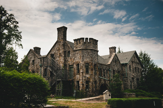 Stone castle with towers and chimneys under cloudy sky