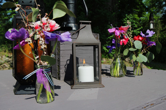 Lanterns with candle and flower arrangements outdoors