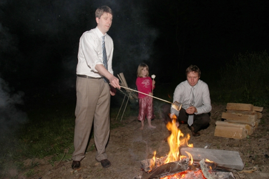 Family roasting marshmallows around a bonfire at night