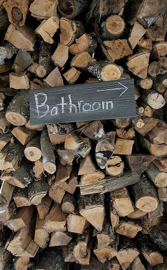Humorous Bathroom sign points right on firewood pile