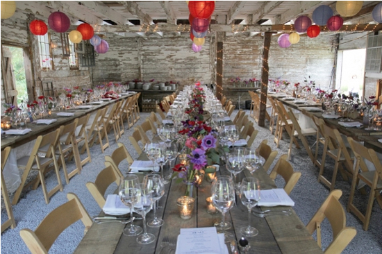 Rustic barn wedding reception with long wooden tables