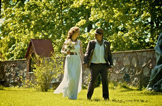 Happy bride and groom stroll through sunny garden