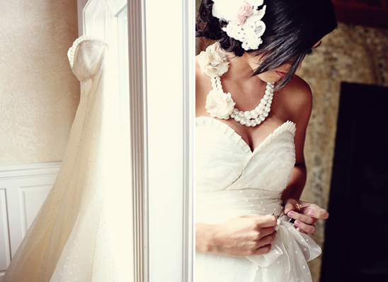 Bride in polka dot wedding dress adjusting her pearls